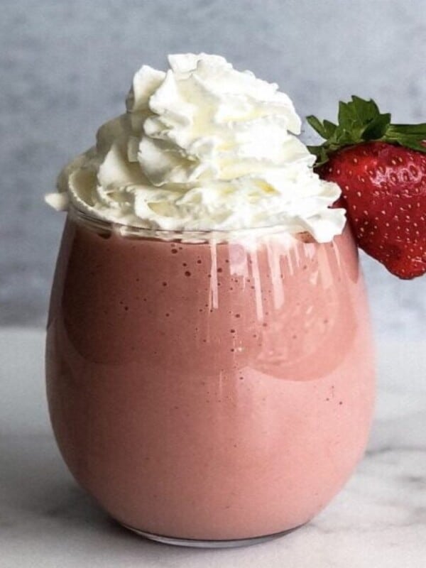 Cantaloupe Mora Smoothie made with cantaloupe, banana, fresh mora, and milk and topped with whipped cream and decorated with a strawberry