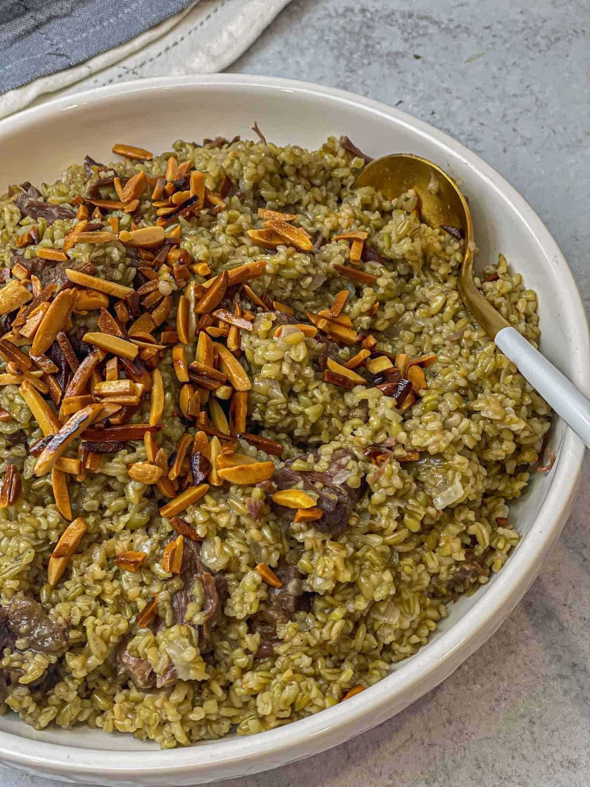 A bowl of freekeh with beef topped with toasted almonds.