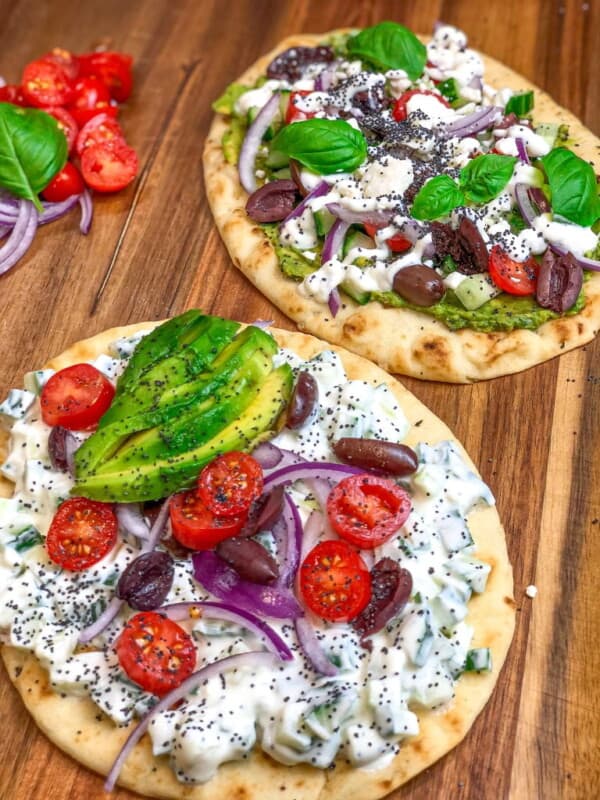 Two naan bread leaves topped with Greek salad