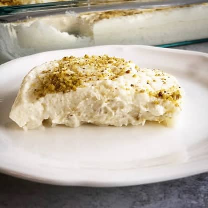 A plate serving a piece of Halawet El Riz, a decadent layered dessert of rice, cheese and ashta!