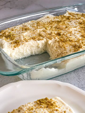 Halawet El Riz a decadent layered dessert of rice, cheese and ashta in a pan topped with ground pistachios