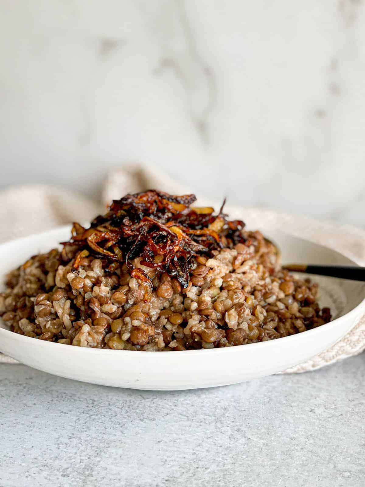 A dish loaded with Lebanese lentils and rice recipe (Mujadaret Roz) topped with caramelized onions.