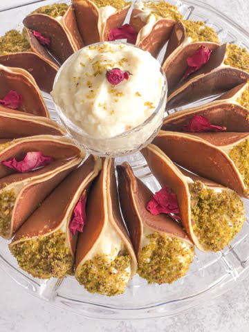 A round plate of Middle Eastern pancakes stuffed with delicious gishta and topped with ground pistachios