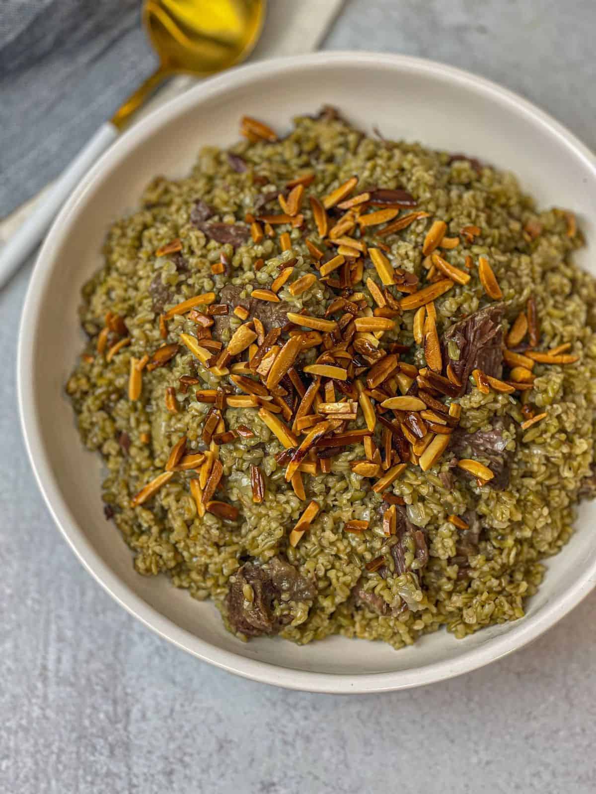 A bowl filled with delicious freekeh with beef and toasted almonds.