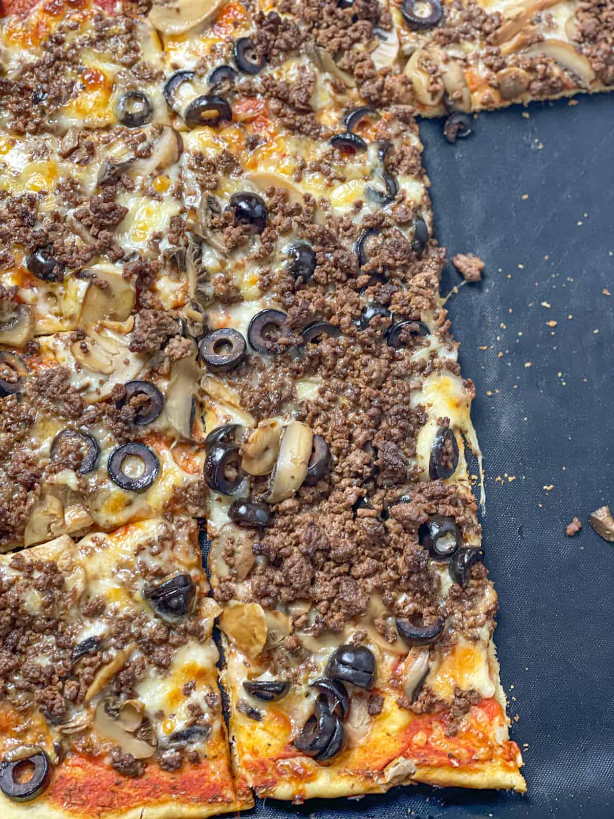 square slices of spicy beef sujuk pizza with olives and mushrooms