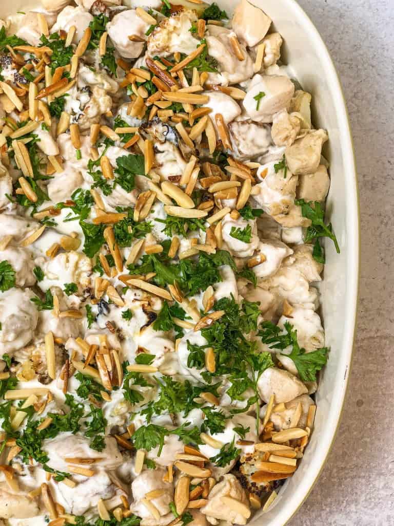 Roasted cauliflower tossed in a creamy tahini sauce, topped with roasted nuts and baked until golden for a deliciously flavorful and nutritious dish.