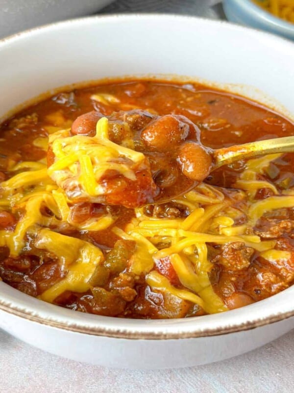 A big bowl of thick hearty chili with melted cheddar served hot