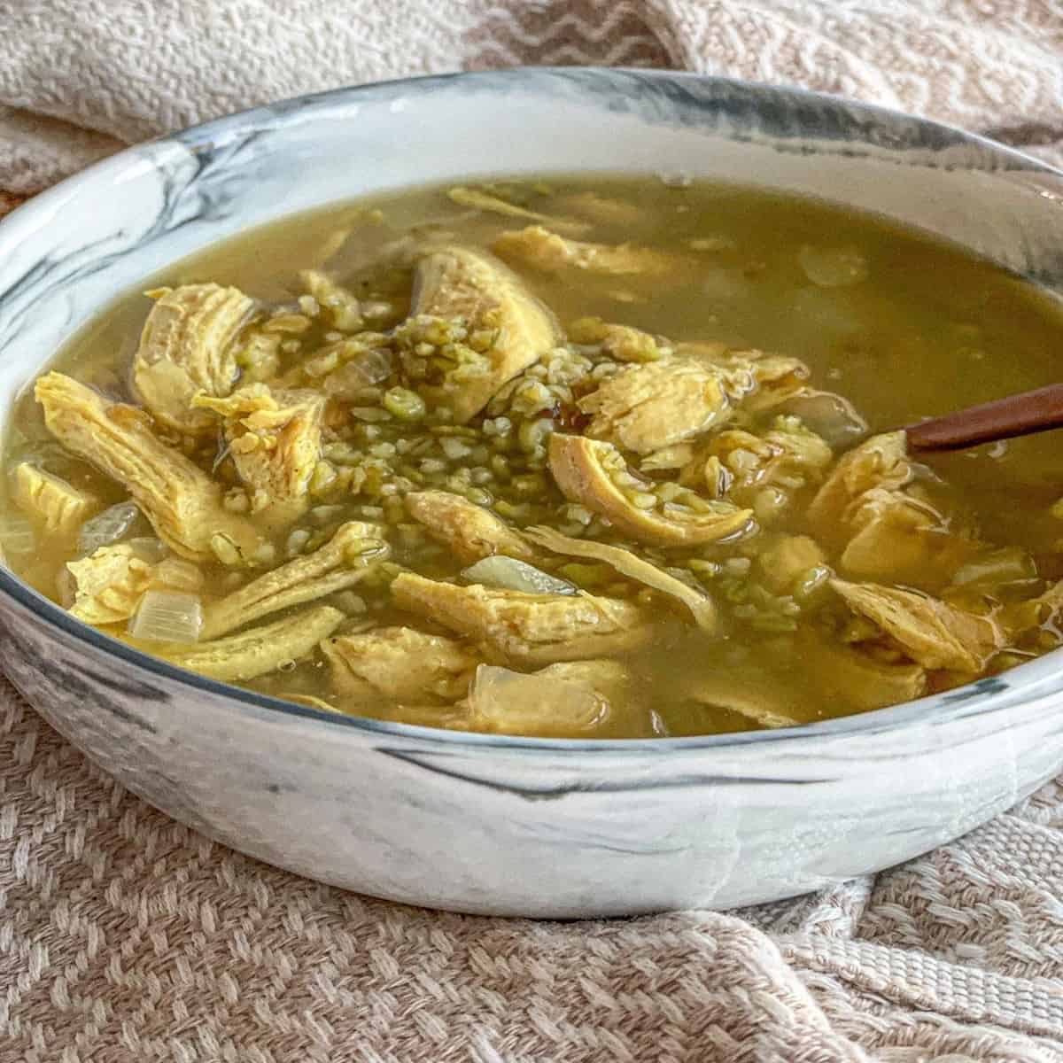 A bowl of durum wheat chicken soup made with durum wheat, chicken breasts, onions, seven spices, and turmeric