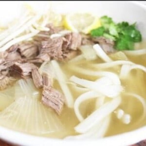 Vietnamese pho soup has noodles, steak slices, and savory broth.