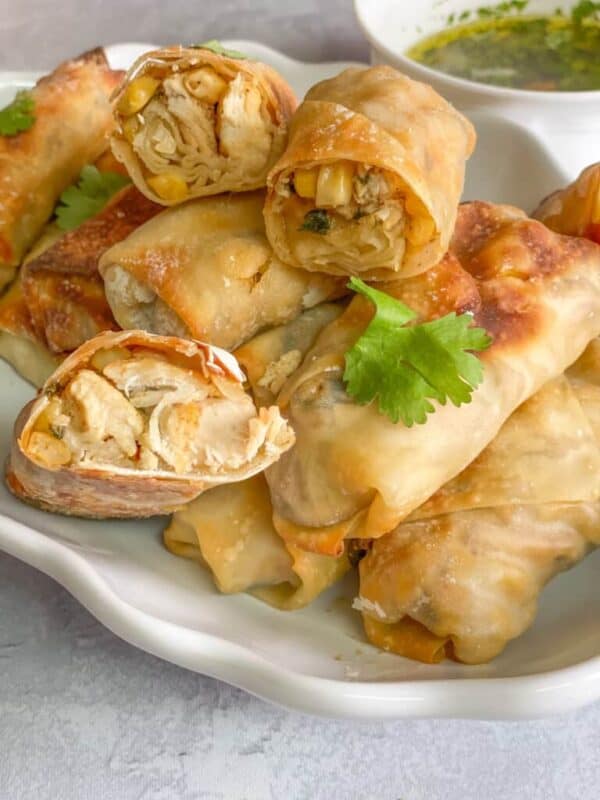 Chicken cilantro eggrolls served on a platter, crispy and golden, with a side of dipping sauce and fresh cilantro garnish.