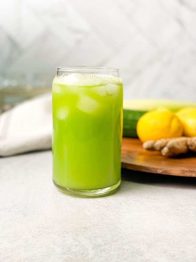 fresh celery juice with ice cubes inside a transparent glass cup