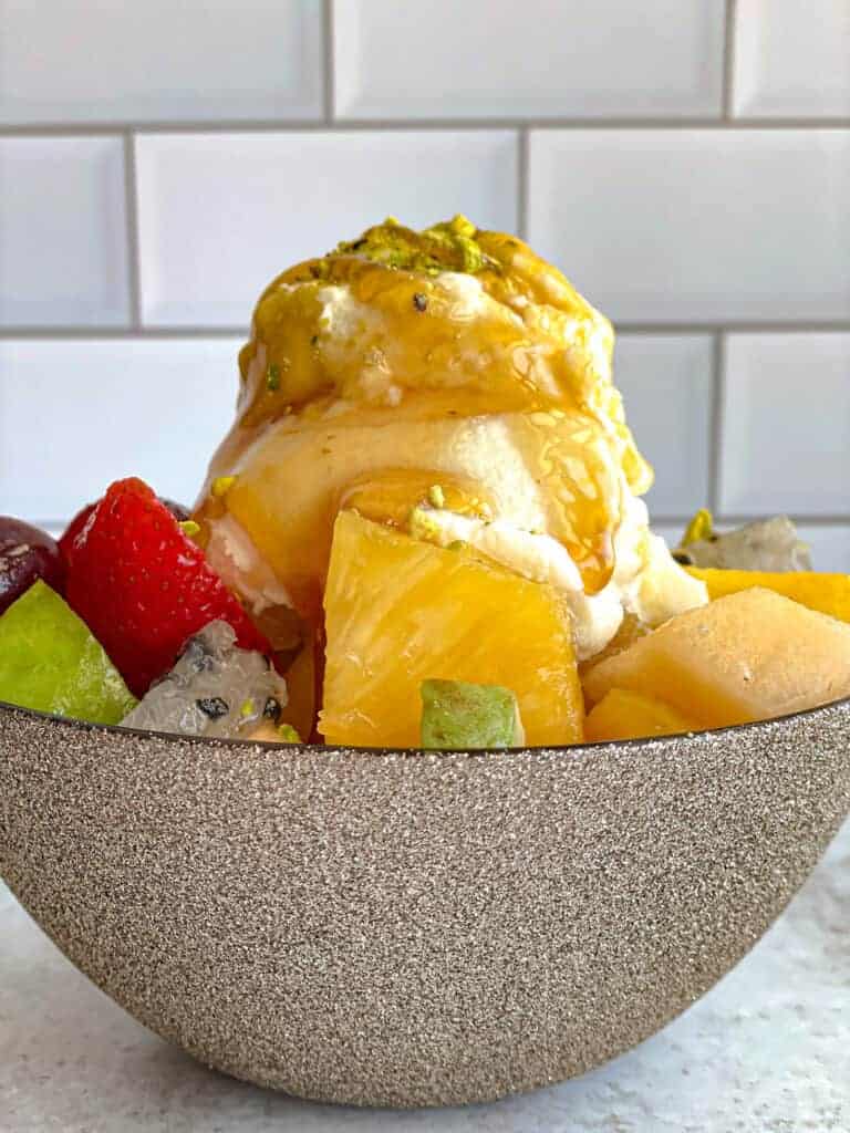 Fruit salad with ashta: A refreshing blend of fresh strawberries, grapes, pineapple, and pear, complemented by creamy ashta (Lebanese clotted cream), topped with pistachios and honey for a decadent treat.