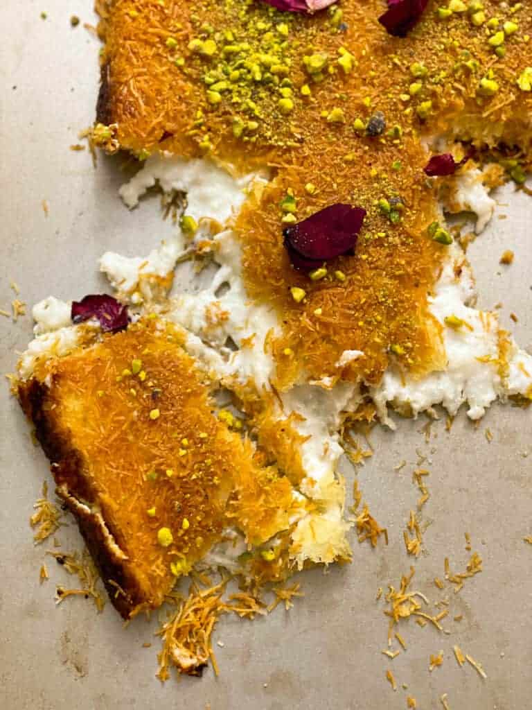 Knefeh: A delectable Middle Eastern dessert featuring layers of shredded phyllo dough, creamy cheese filling, and a golden-brown crust, topped with syrup and pistachios.