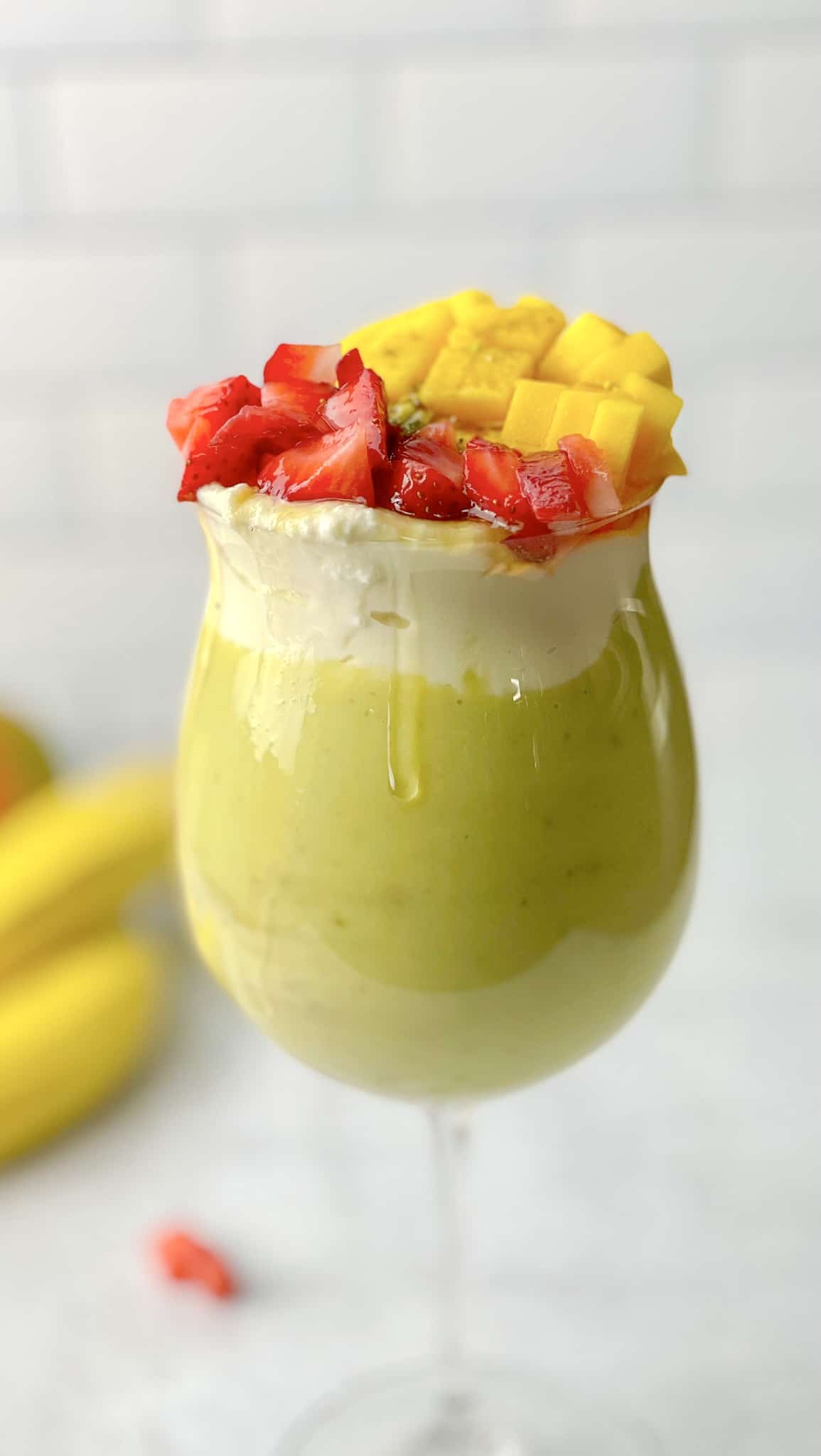 A cup of avocado smoothie topped with a selection of fruit.