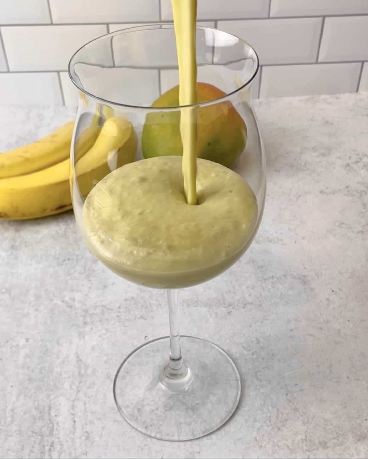 Tasty avocado smoothie being poured into a glass.