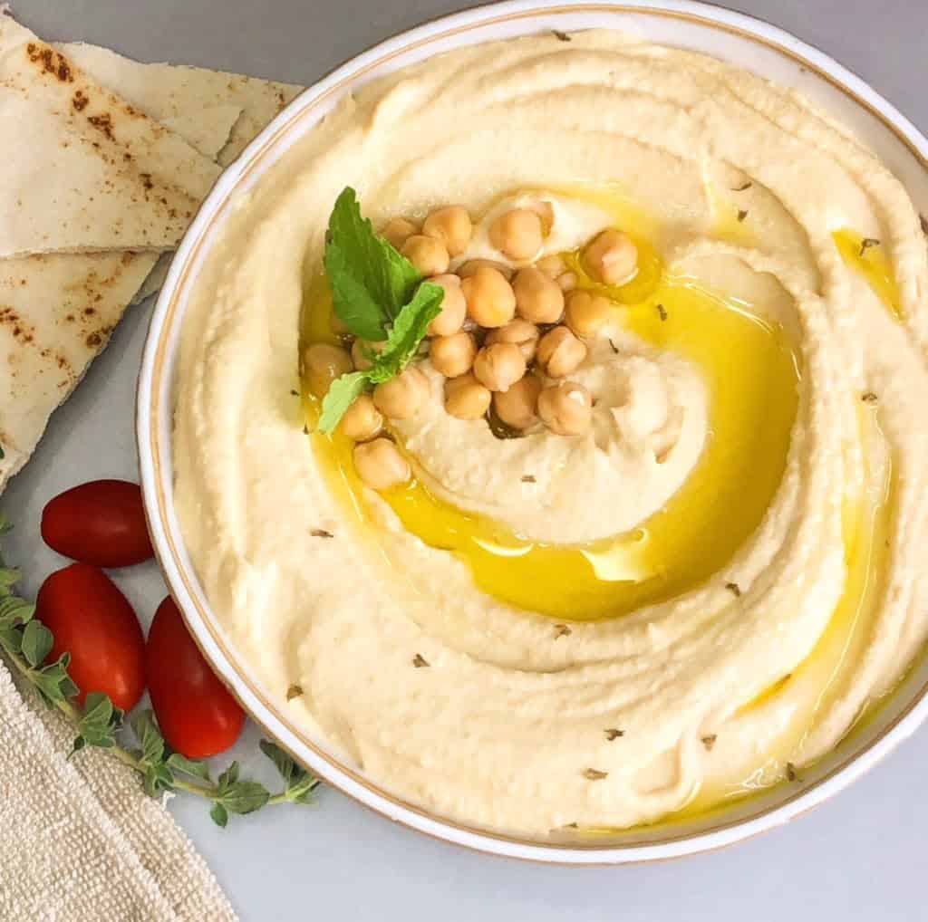 A delicious soft and smooth Hummus with Tahini plate served with a topping of hummus and mint.