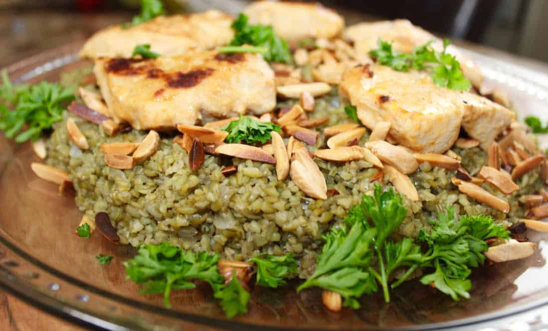 Delicious Freekeh served with ginger chicken on a decorative brown plate.