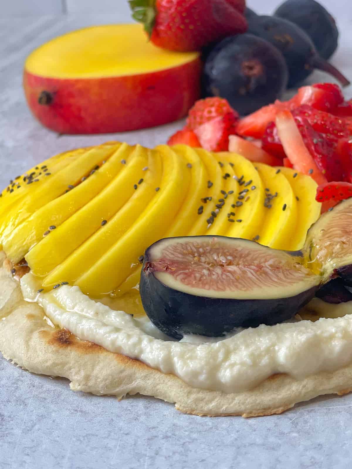 A delightful flatbread adorned with creamy ricotta cheese and a colorful assortment of fresh fruits, offering a perfect balance of sweetness and indulgence.