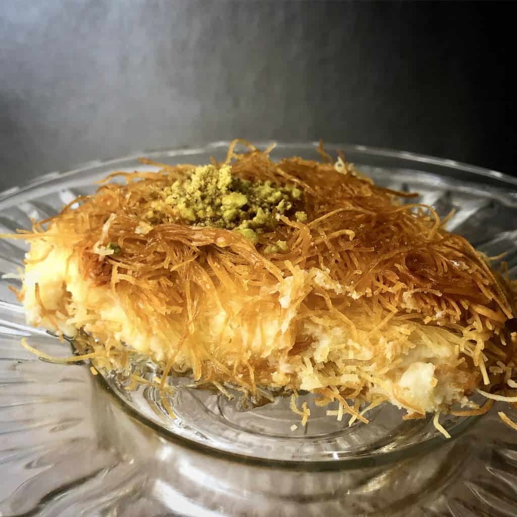 Layers of crispy shredded phyllo dough filled with creamy ashta (clotted cream), drizzled with syrup for a delectably sweet and indulgent Middle Eastern dessert.