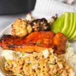 air fryer BBQ salmon served on a white platter with Mexican corn, crispy cauliflower, and avocado slices