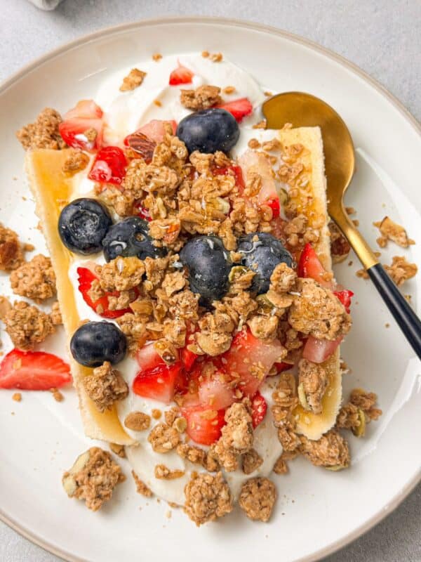 A breakfast spread featuring a Greek Yogurt Banana Split topped with granola, berries, and honey.