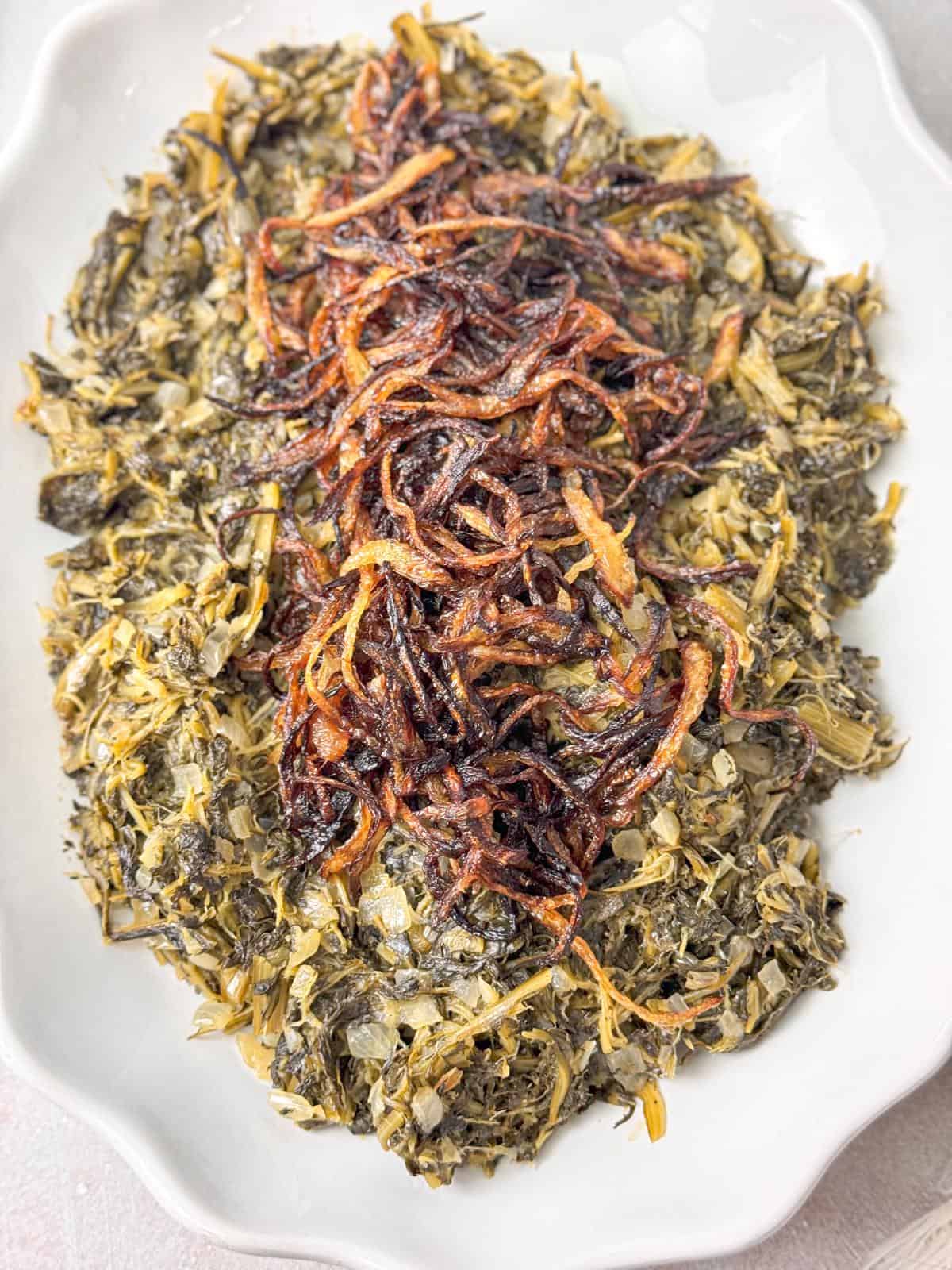 Freshly prepared Hindbeh salad with tender dandelion greens, caramelized onions, and a sprinkle of sumac.