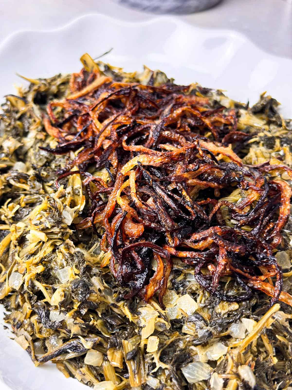 Traditional Lebanese dandelion salad with caramelized onions on a white serving dish.