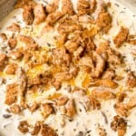 A top shot of tender juicy garam masala chicken submerged in white creamy mushroom sauce