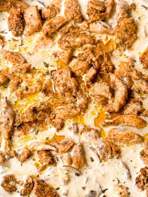 A top shot of tender juicy garam masala chicken submerged in white creamy mushroom sauce