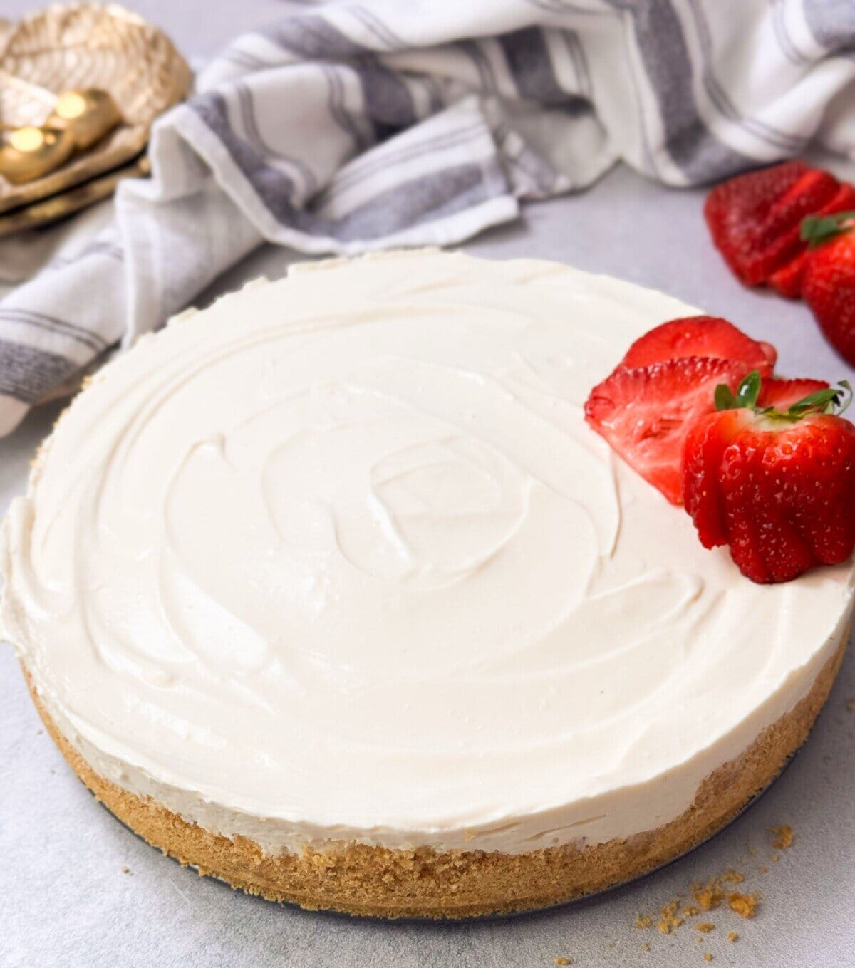 a shot of no-bake cheesecake with a crunchy crust and cheesecake filling with sliced fresh strawberries on top