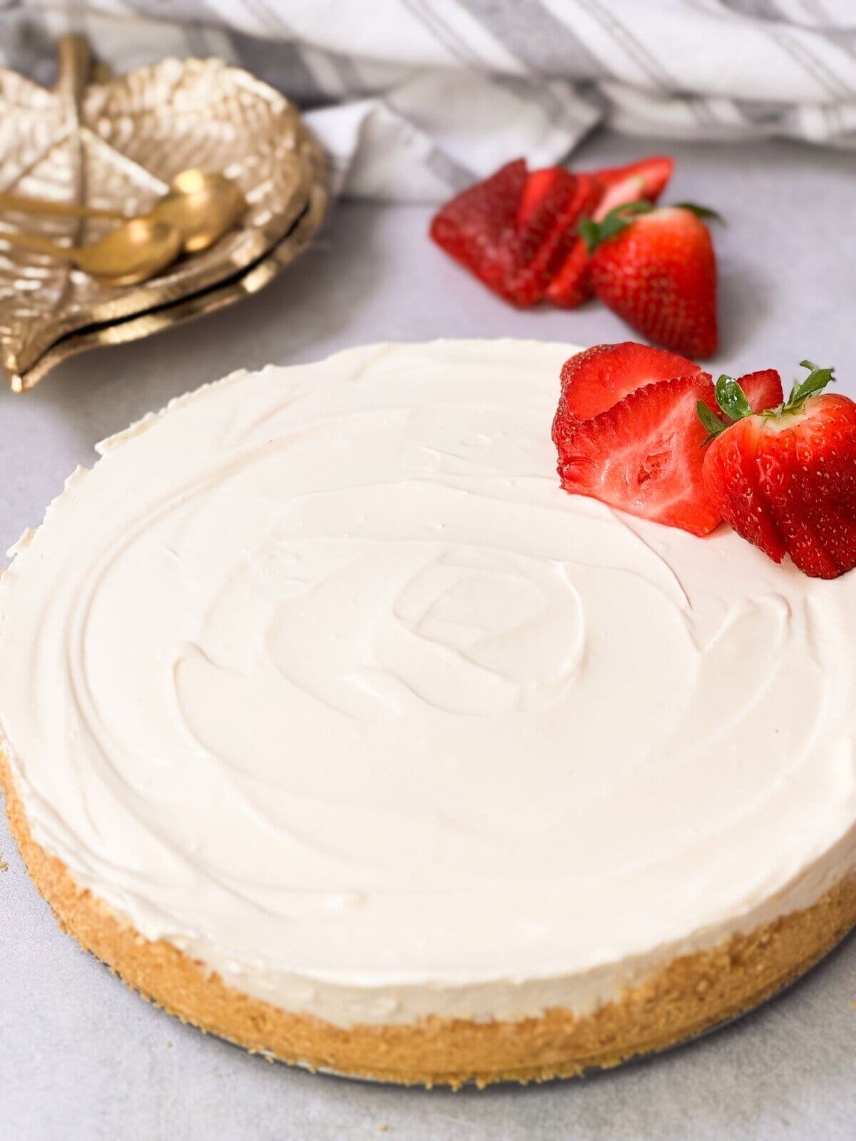 a shot of no-bake cheesecake with a crunchy crust and cheesecake filling with sliced fresh strawberries on top