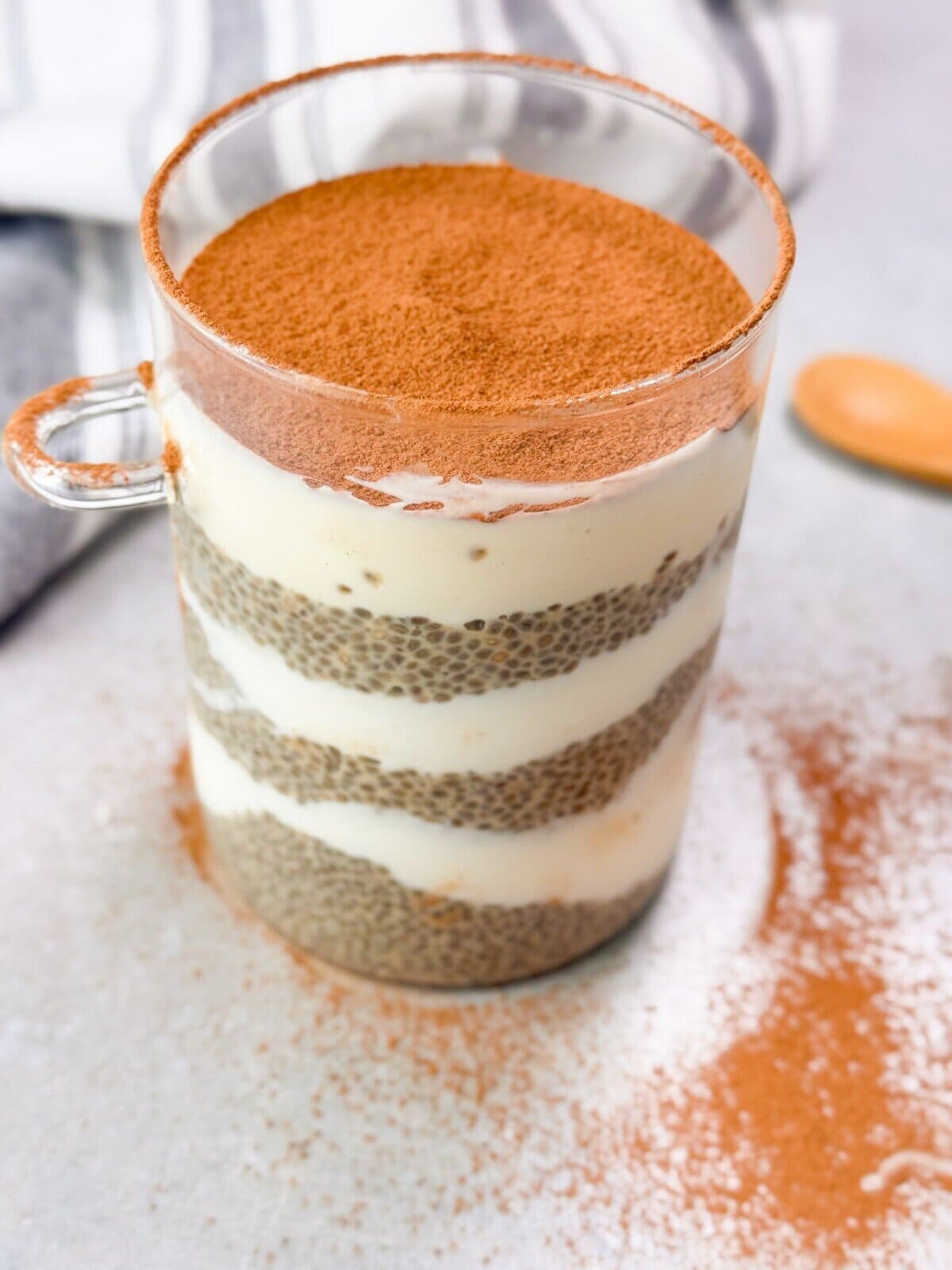 a glass cup showing the creamy layers of tiramisu chia seed pudding