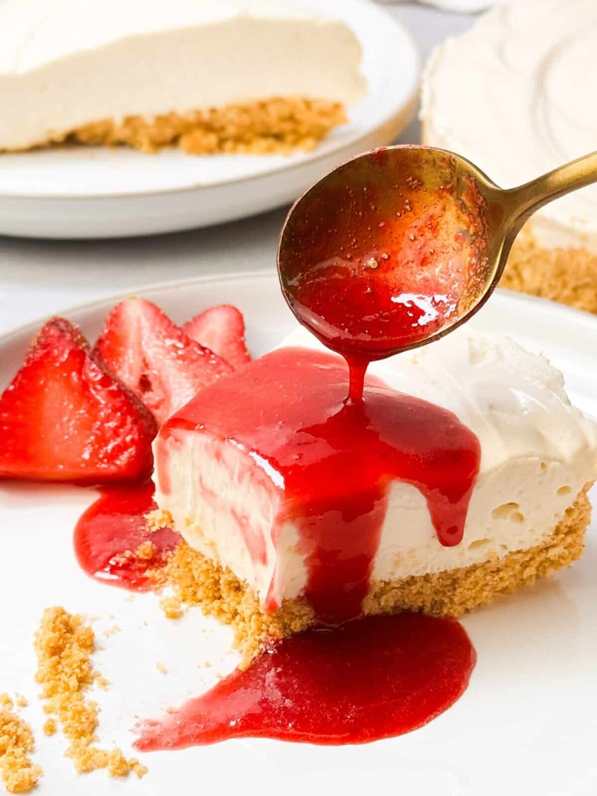 a shot of drizzling a spoonful of strawberry rosemary sauce over a slice of no bake cheesecake