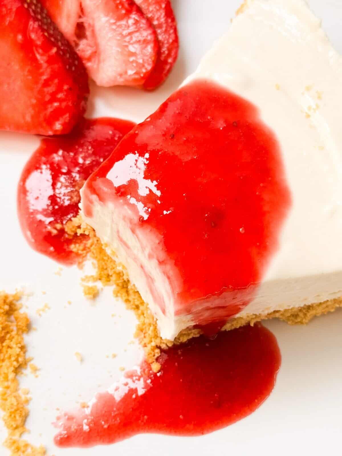 a top shot of a slice of no bake cheesecake with strawberry rosemary sauce on top