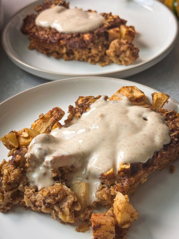 apple cinnamon oatmeal bake topped with yogurt frosting served in a white plate