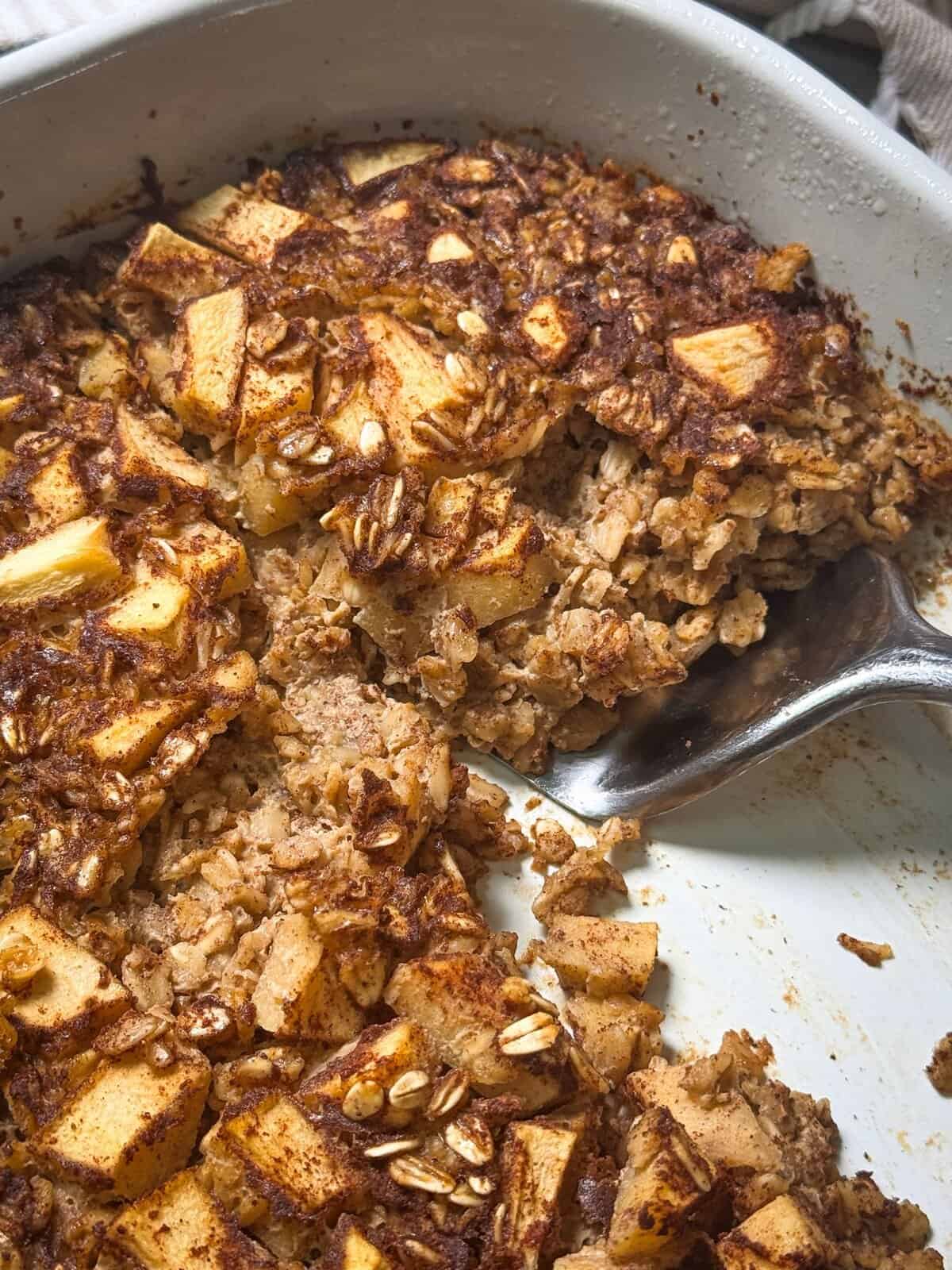 Apple Cinnamon Baked Oatmeal serving cinnamon apple baked oatmeal with spatula from tray