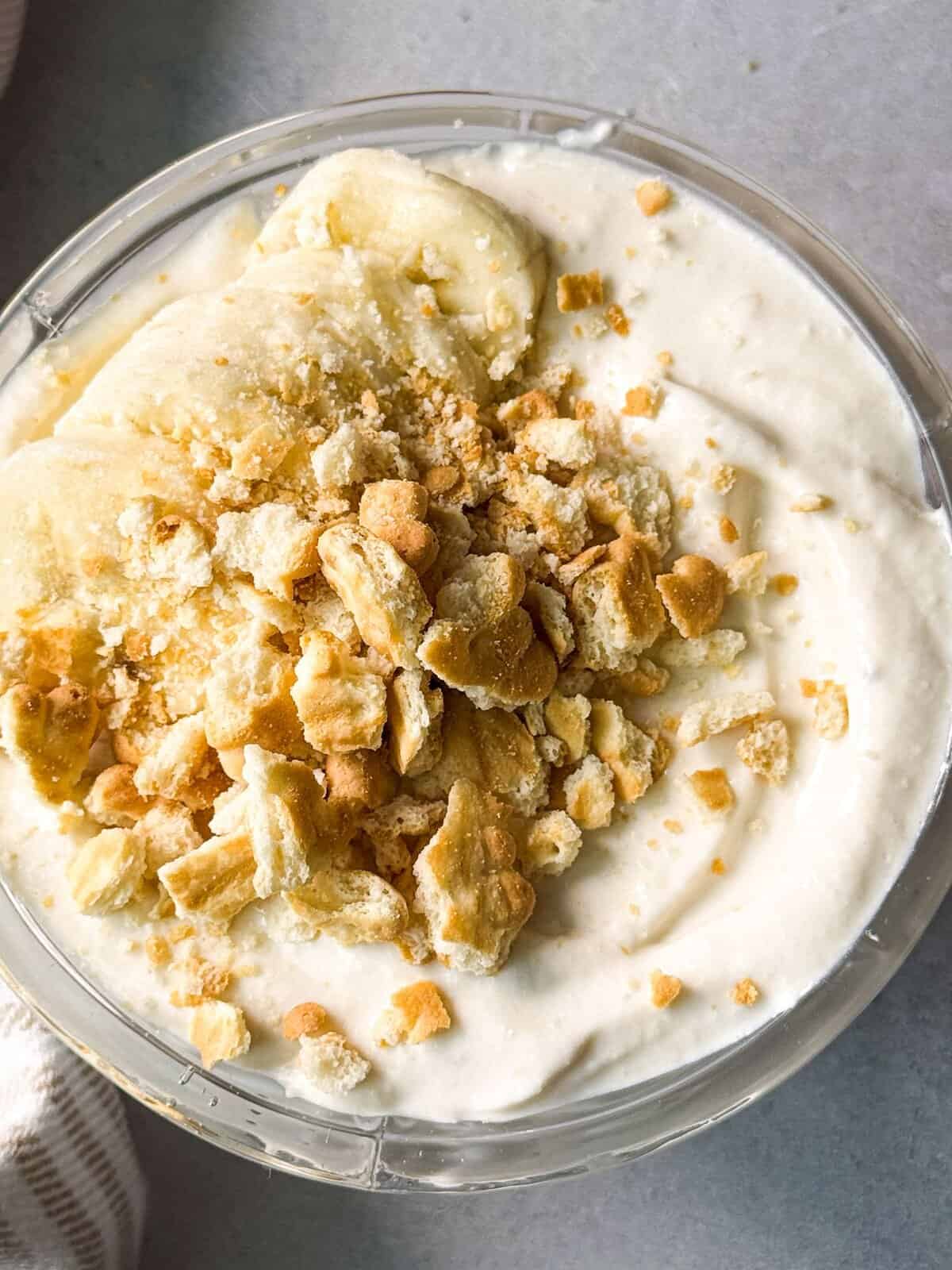 top of banana cottage cheese pudding topped with biscuit pieces served in a crystal glass serving cup