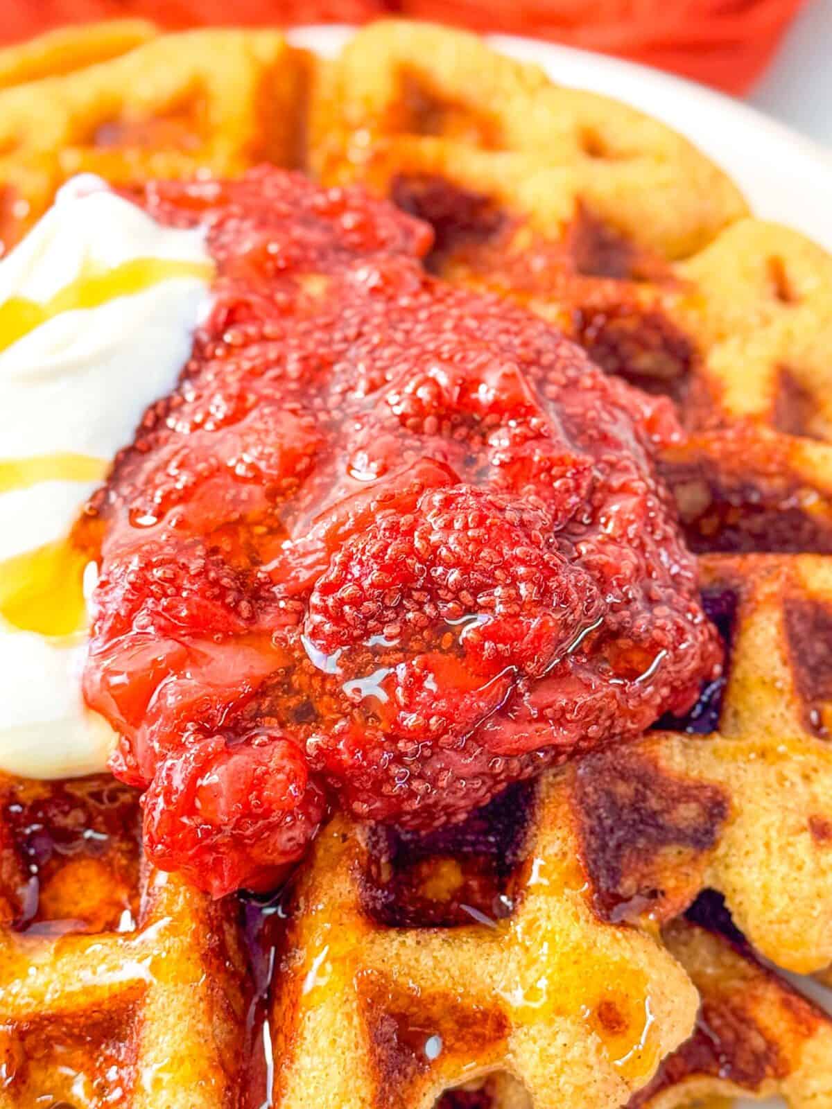 10 Minute Strawberry Chia Seed Jam golden waffles topped with strawberry chia jam, a dollop of yogurt, and drizzled with honey