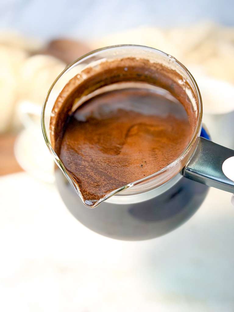 Authentic Turkish Coffee Freshly brewed Turkish coffee in a small glass pot (cezve), showing a thick layer of foam on top.