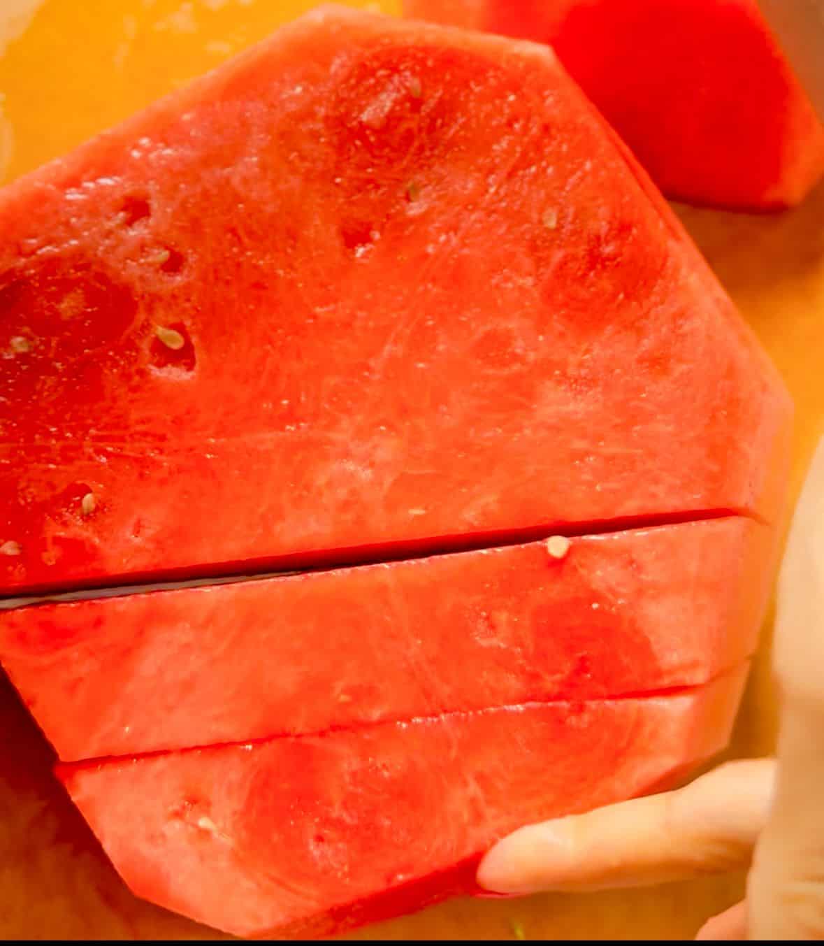 With the watermelon half still flat on the board, cut it into even slices about ½ inch thick.