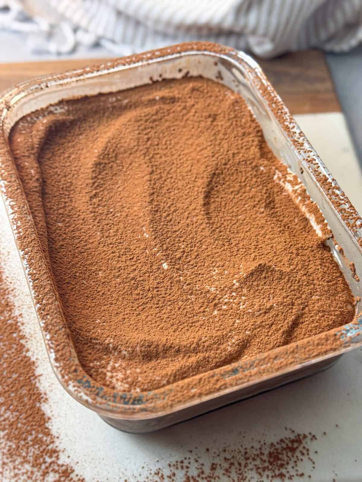 Chocolatey Mocha Chia Pudding Cake glass dish of high protein mocha chia pudding cake dusted with cocoa powder.