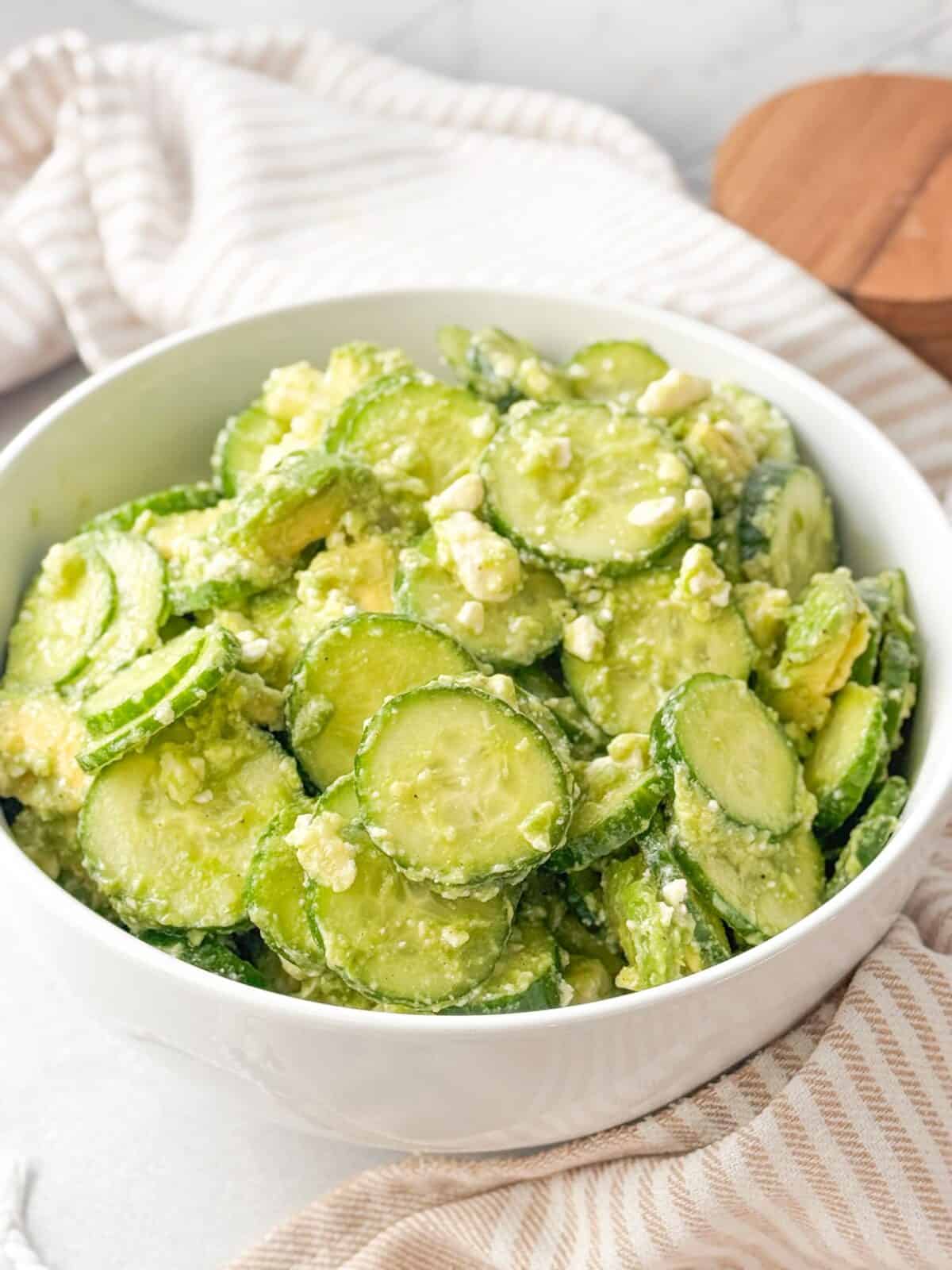 Cucumber Avocado Feta Salad A shot of crisp cucumber avocado feta salad served in a white bowl. The salad features sliced cucumbers mixed with creamy avocado chunks and crumbled feta cheese