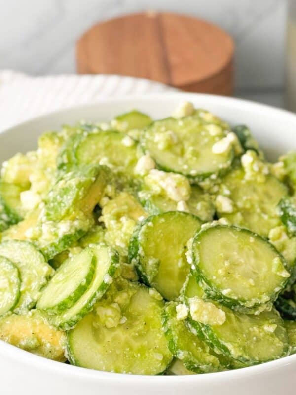 A close-up shot of fresh cucumber feta salad served in a white bowl.