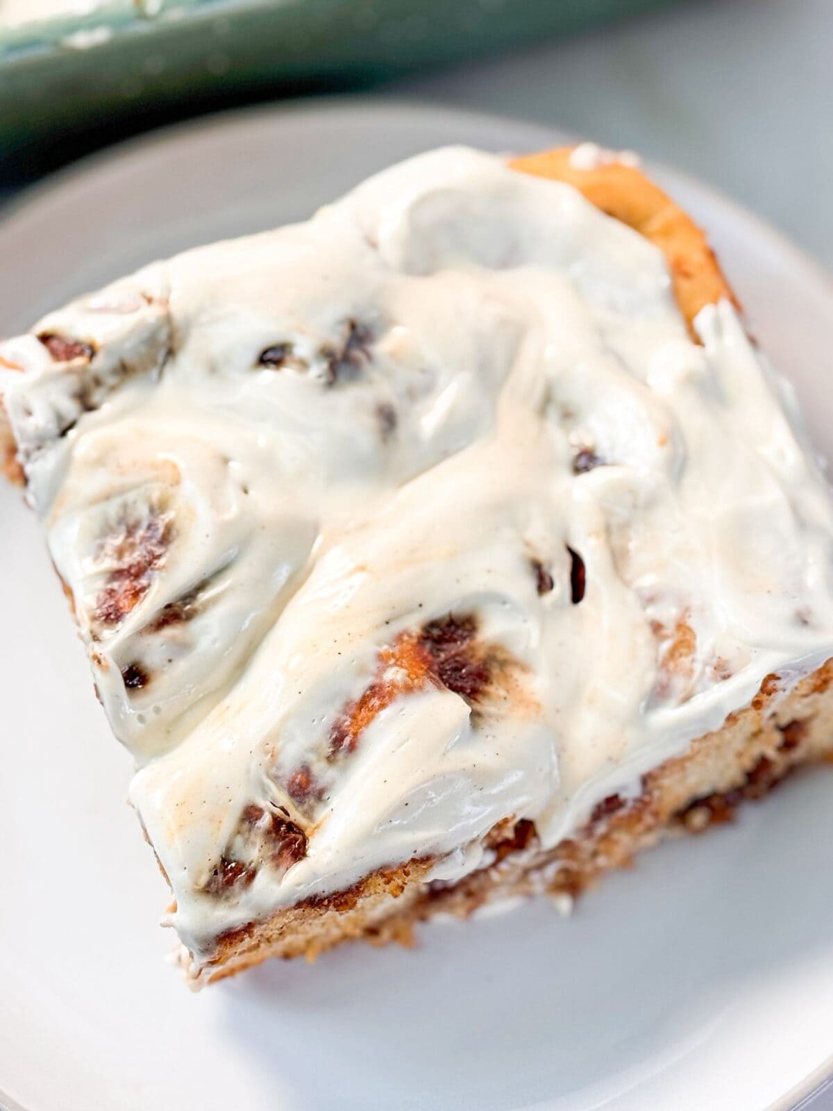 Easy Cinnamon Roll Focaccia a top shot of a slice of fluffy soft cinnamon roll focaccia topped with cream cheese icing