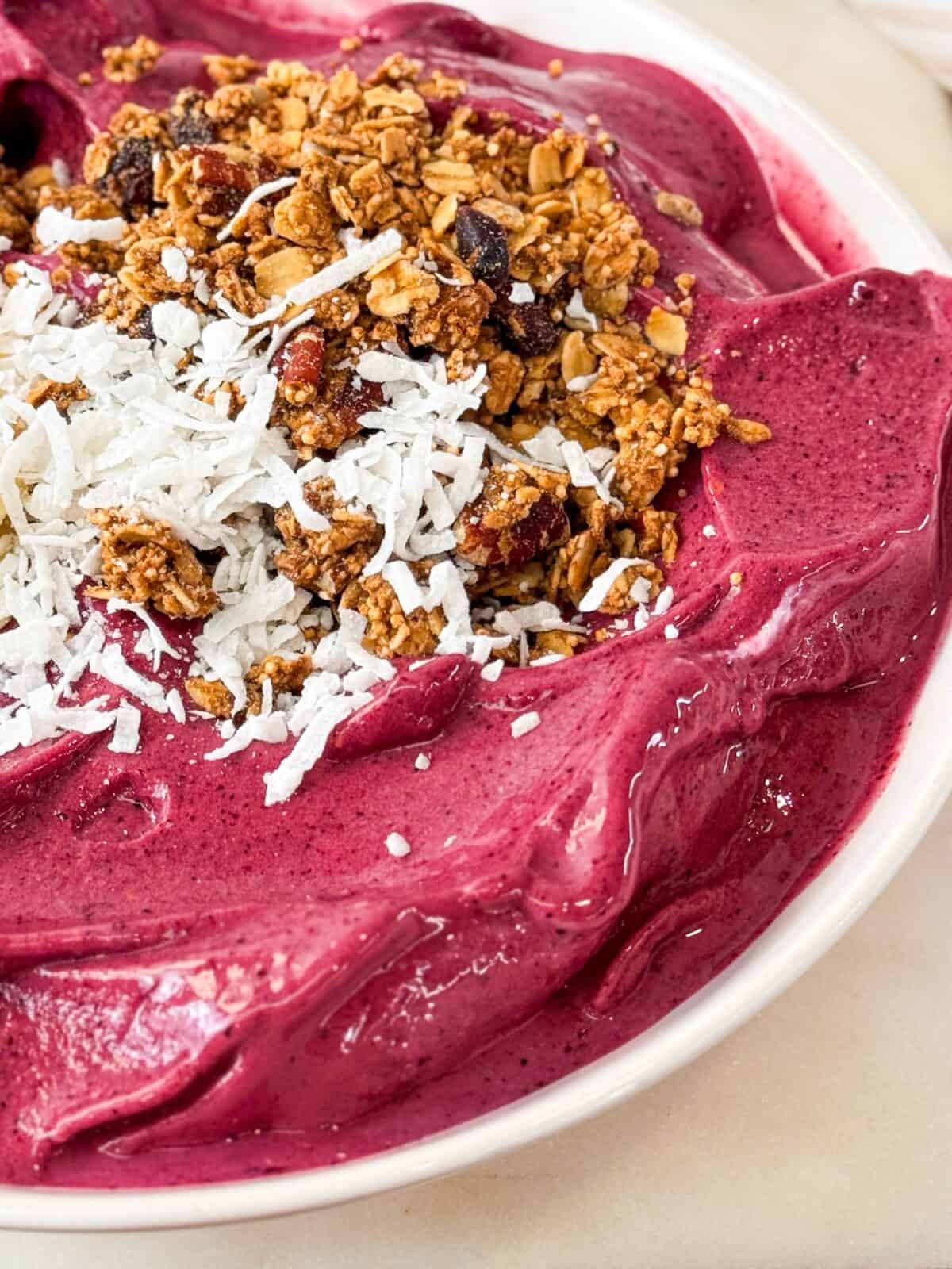 Frozen Mixed Berry Smoothie Bowl a close-up shot of a thick and creamy berry smoothie bowl topped with granola and shredded coconut
