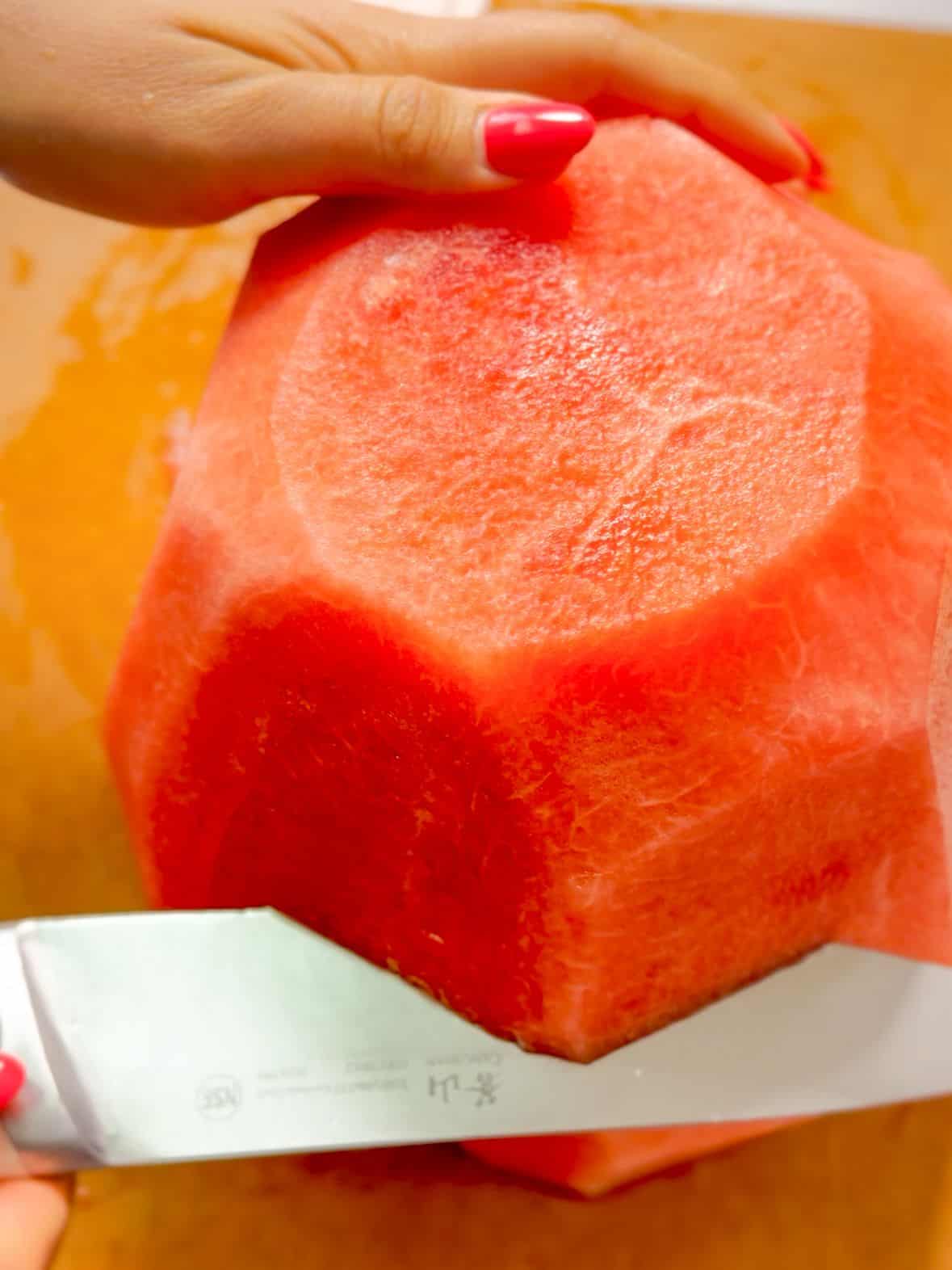 Stand the watermelon upright on one of the flat ends. Cut it straight down the middle to create two large halves.