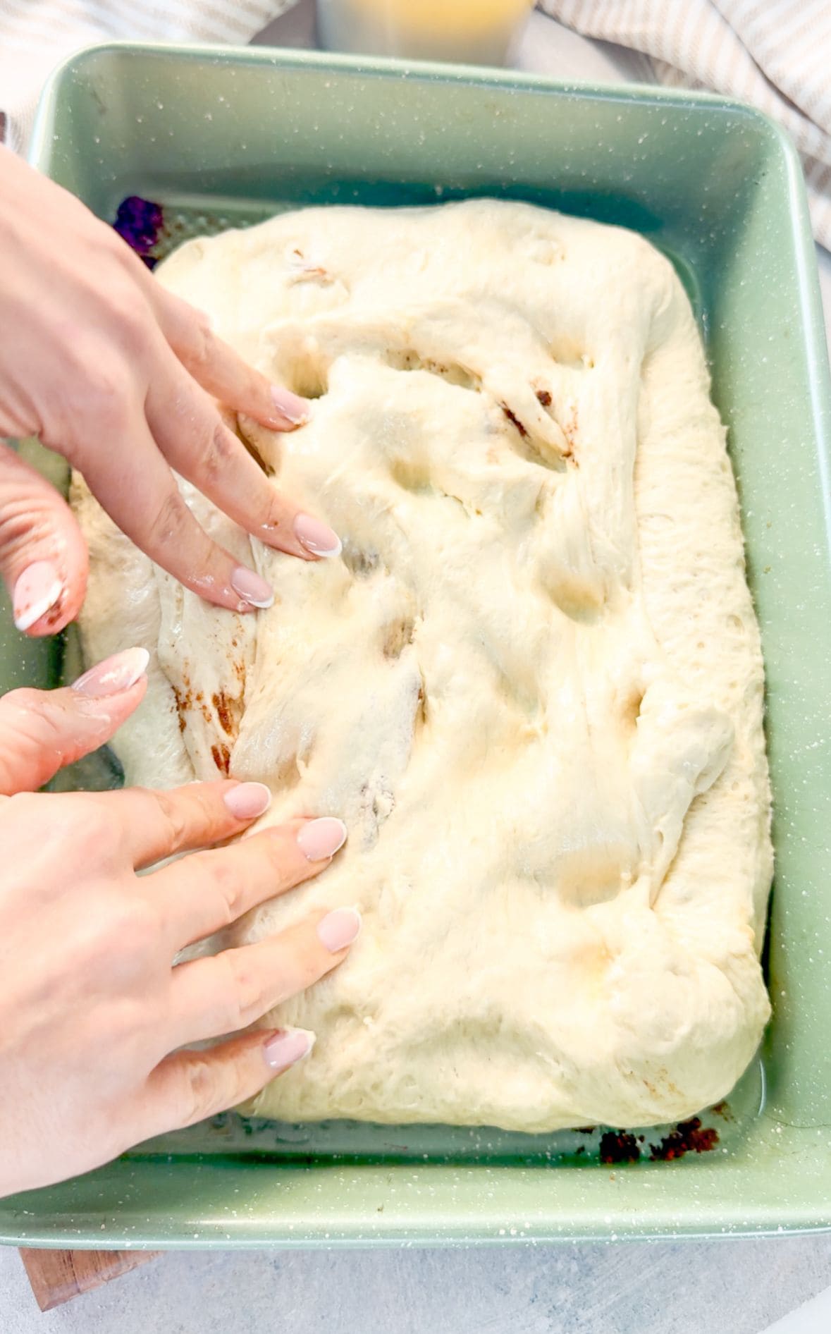 How to Make Cinnamon Roll Focaccia A woman slides dough directly onto a lightly oiled pan