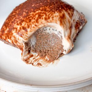 A close-up look at the mocha chia pudding cake, with a bite taken out to reveal the creamy, chocolatey interior, served on a white plate.