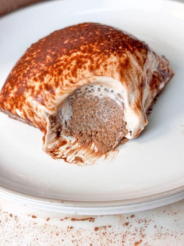 A close-up look at the mocha chia pudding cake, with a bite taken out to reveal the creamy, chocolatey interior, served on a white plate.