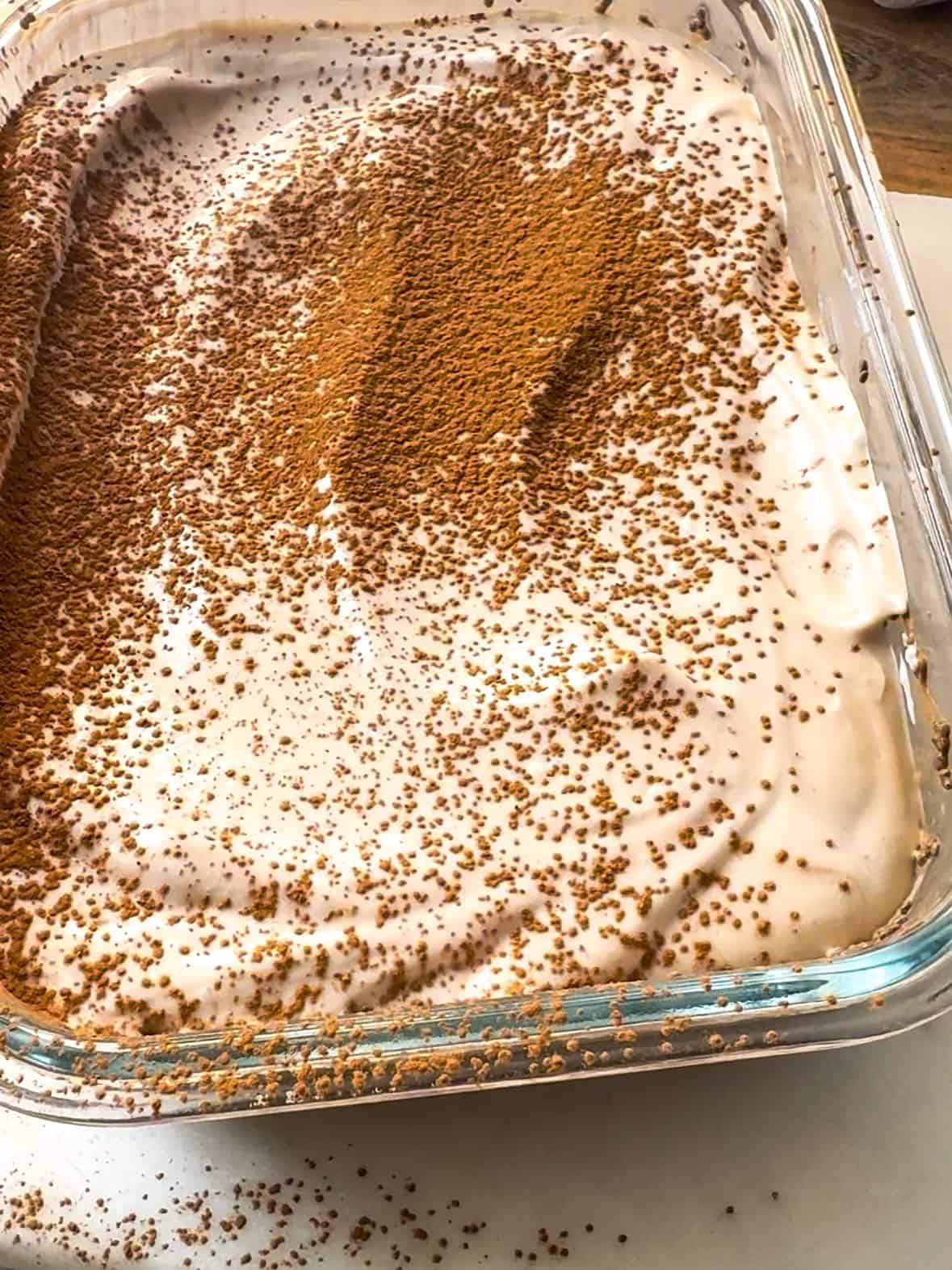 Mocha Chia Pudding Cake Recipe a shot of a pirex dish of mocha chia pudding cake dusted with extra cacao powder.